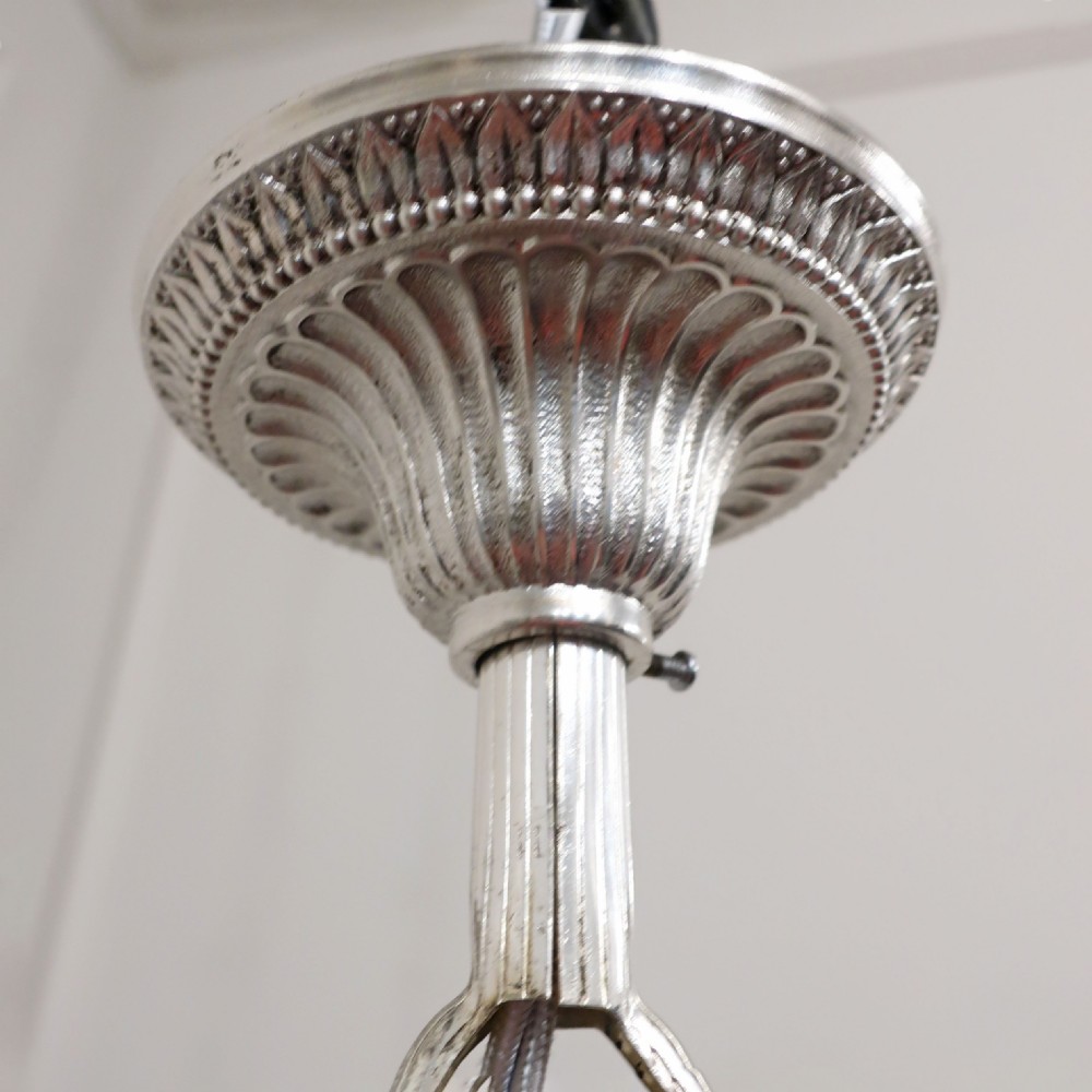 A French silver six-arm ceiling chandelier featuring sweeping curved branches, decorative rosettes, cream candle sleeves, and a turned central column hanging from a chain link. View XIII