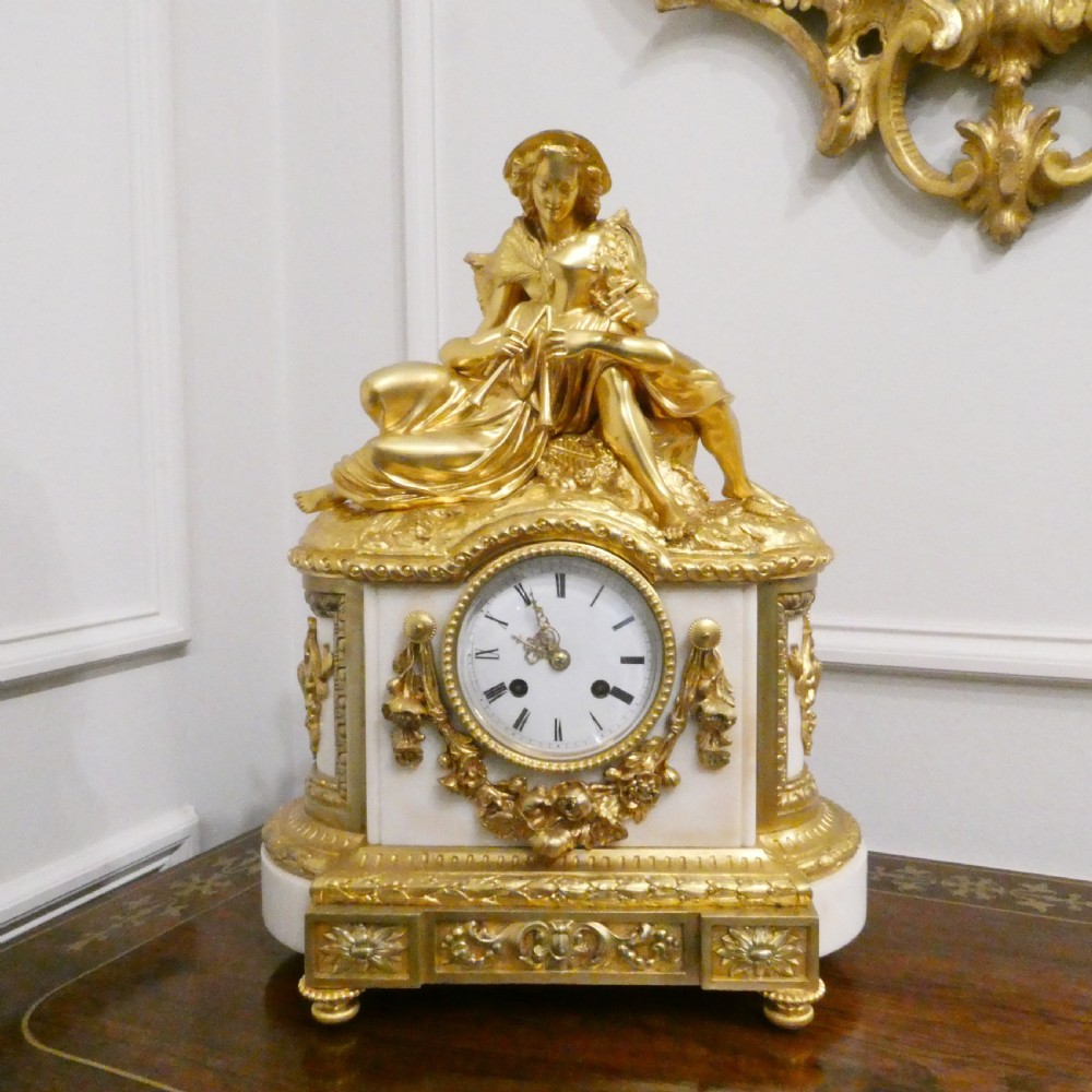 A French gilt bronze and white marble mantel clock featuring a classical figural sculpture on top and decorative floral mounts around the dial. View II