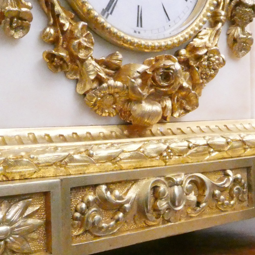 A French gilt bronze and white marble mantel clock featuring a classical figural sculpture on top and decorative floral mounts around the dial. View VIII