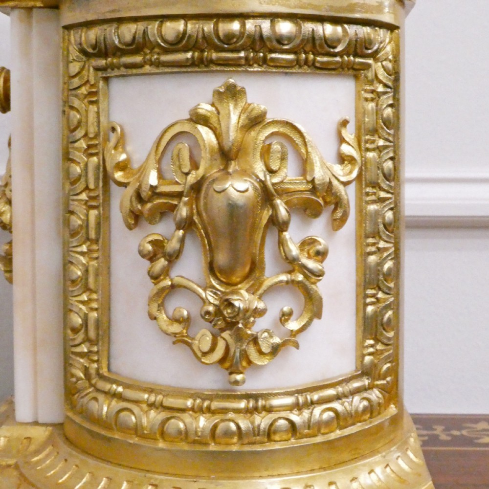 A French gilt bronze and white marble mantel clock featuring a classical figural sculpture on top and decorative floral mounts around the dial. View XII