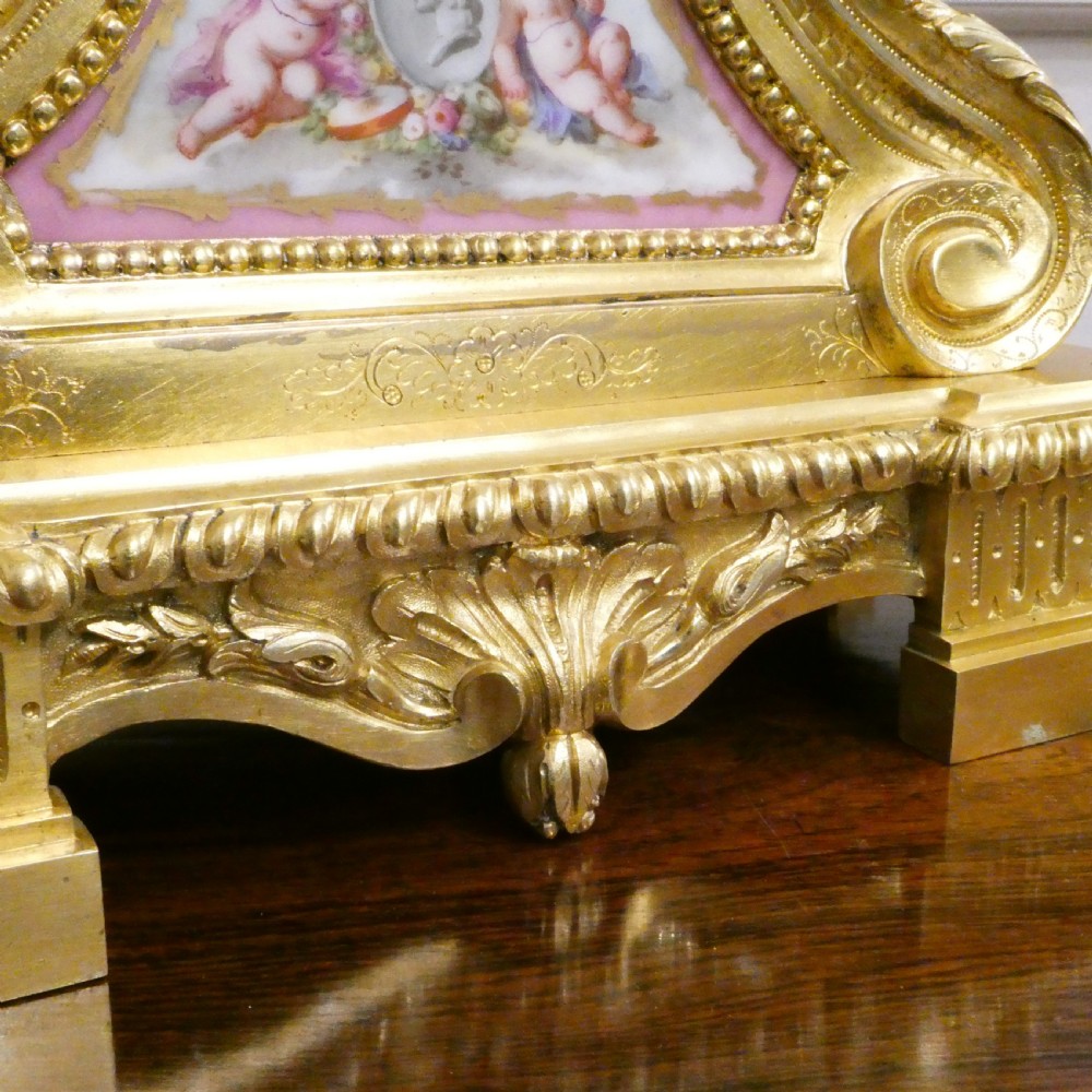 A French Louis XV style gilt bronze mantel clock featuring a hand-painted porcelain dial, lower cherub panel, scroll feet, and an ornamental urn finial. View IX