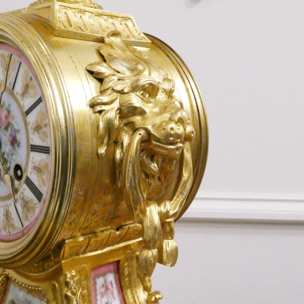 A French Louis XV style gilt bronze mantel clock featuring a hand-painted porcelain dial, lower cherub panel, scroll feet, and an ornamental urn finial. View XI