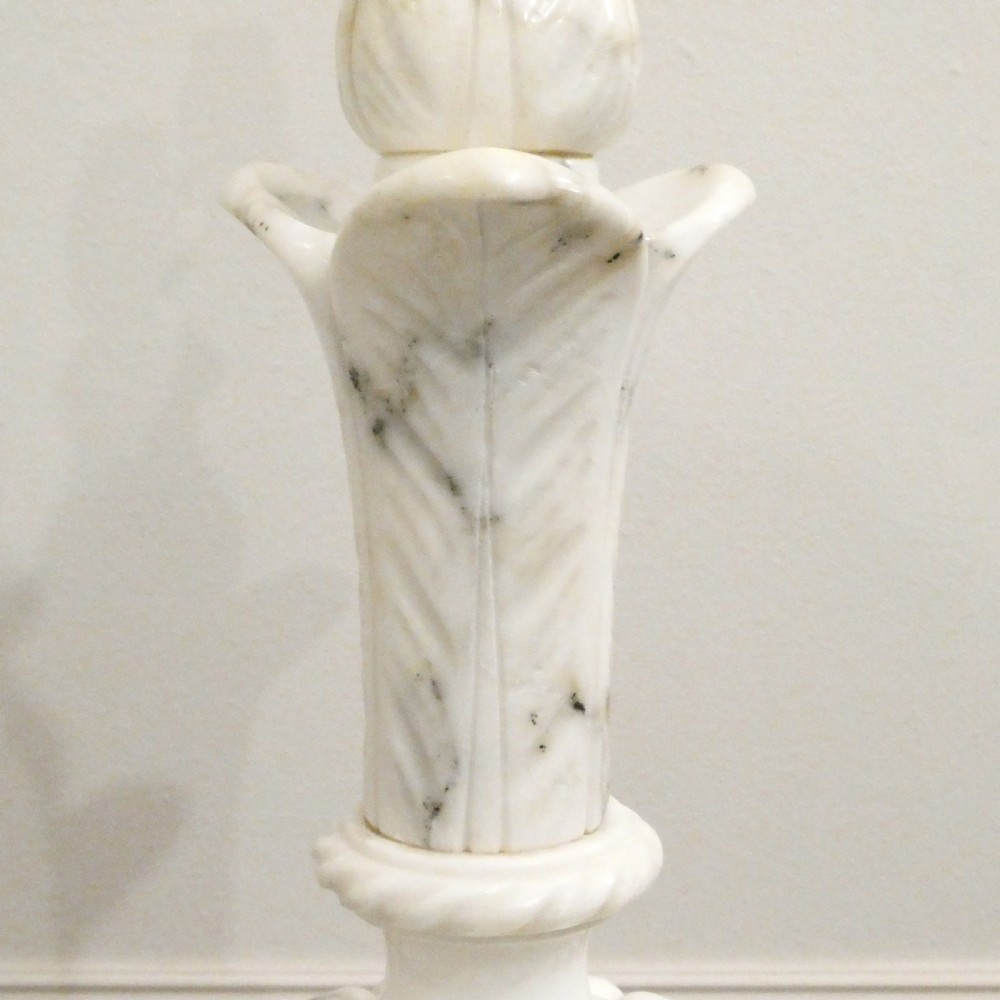 An early 20th-century carved white alabaster table lamp featuring an urn-shaped stem, square plinth base, and a pleated white fabric lampshade. View V
