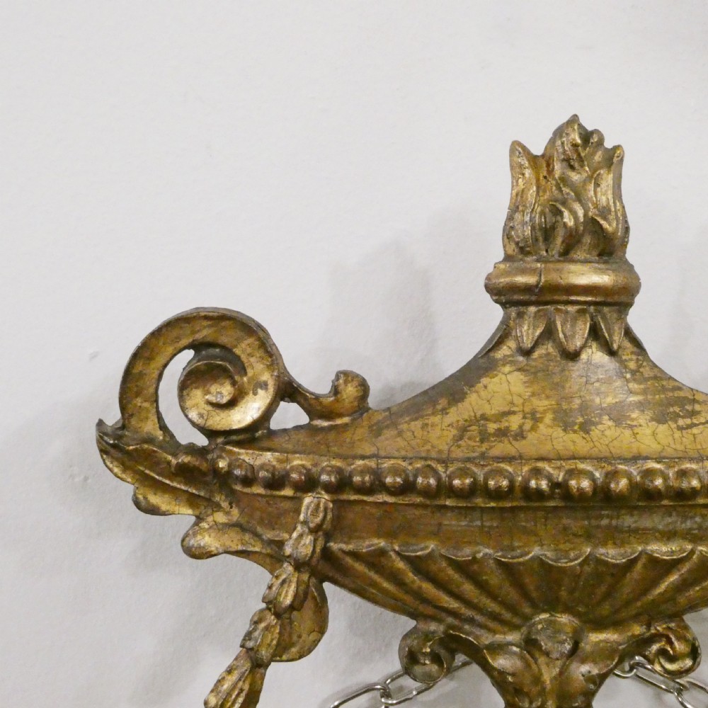 An oval giltwood wall mirror featuring Neoclassical urn cresting, suspended husk festoons with bow ribbons, and lower decorative scrollwork. View IV