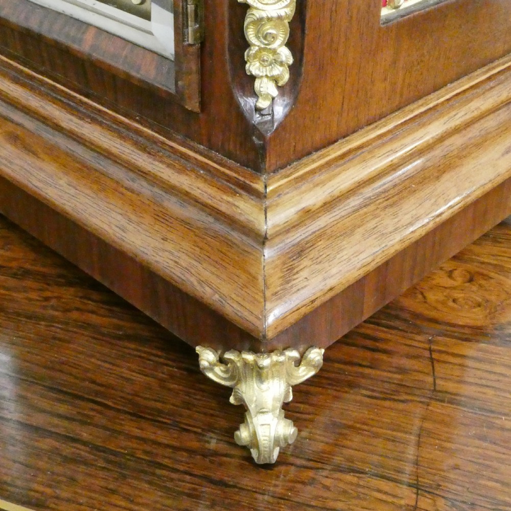 A dark mahogany arched bracket clock featuring gilt brass corner mounts, finials, and a silvered chapter ring dial with brass spandrels. View IV