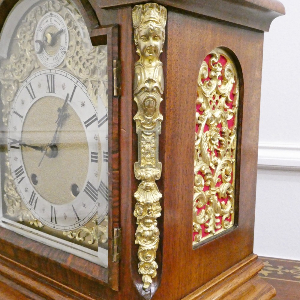 A dark mahogany arched bracket clock featuring gilt brass corner mounts, finials, and a silvered chapter ring dial with brass spandrels. View V