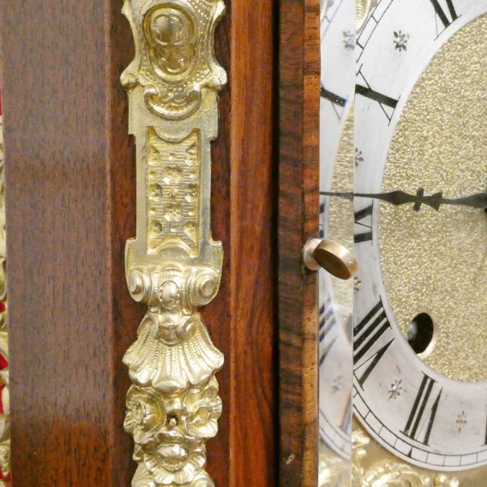 A dark mahogany arched bracket clock featuring gilt brass corner mounts, finials, and a silvered chapter ring dial with brass spandrels. View VI