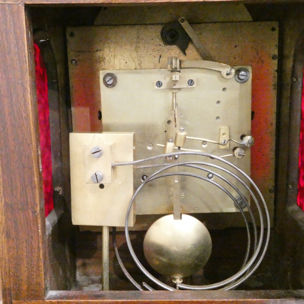 A dark mahogany arched bracket clock featuring gilt brass corner mounts, finials, and a silvered chapter ring dial with brass spandrels. View XI