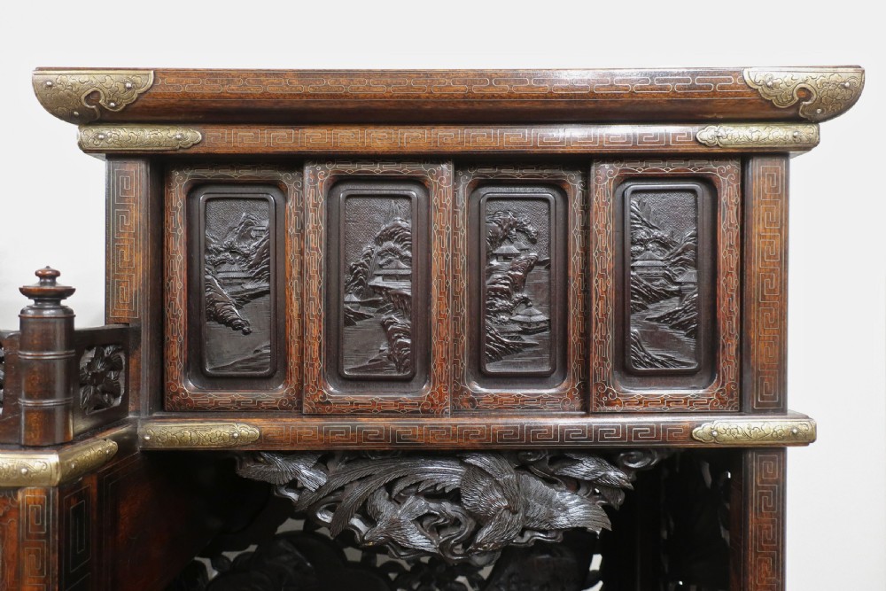 A dark carved hardwood Japanese Meiji period shodana cabinet featuring asymmetrical shelves, relief-carved panel doors, metal mounts, and a carved lower base. View III