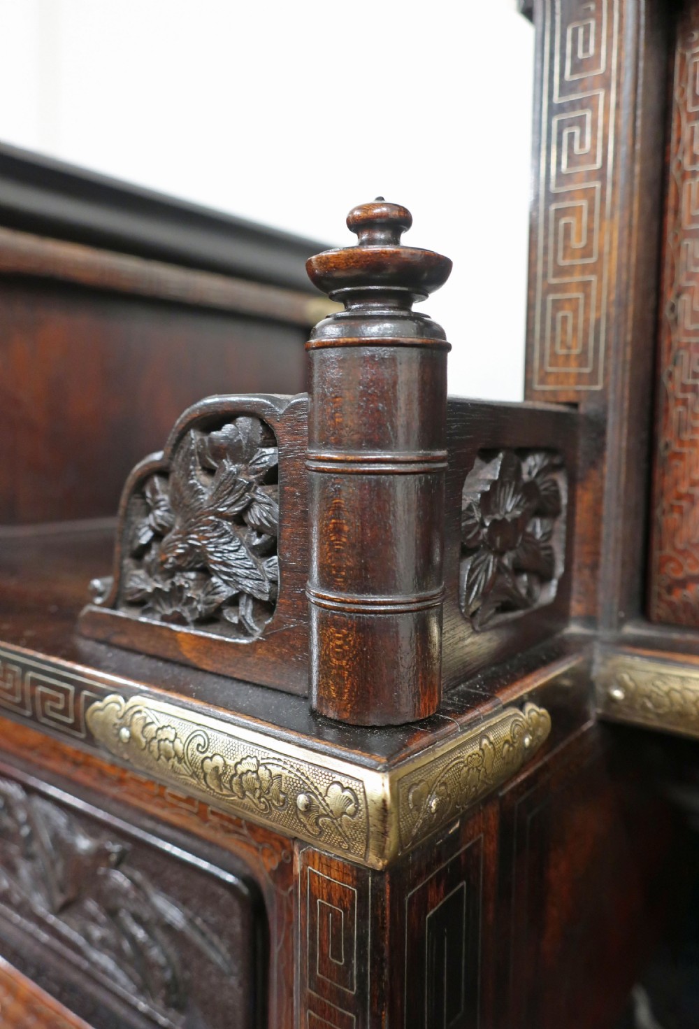 A dark carved hardwood Japanese Meiji period shodana cabinet featuring asymmetrical shelves, relief-carved panel doors, metal mounts, and a carved lower base. View V