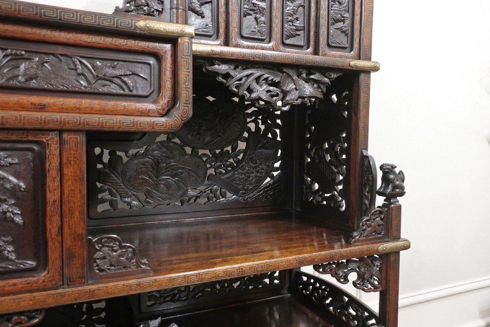 A dark carved hardwood Japanese Meiji period shodana cabinet featuring asymmetrical shelves, relief-carved panel doors, metal mounts, and a carved lower base. View VIII