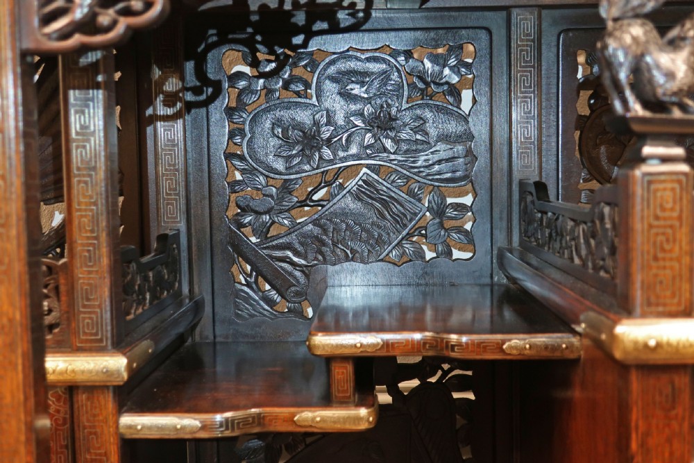 A dark carved hardwood Japanese Meiji period shodana cabinet featuring asymmetrical shelves, relief-carved panel doors, metal mounts, and a carved lower base. View X