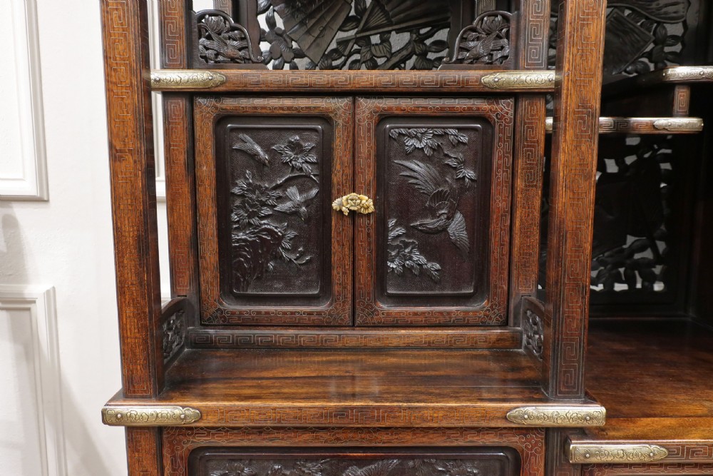 A dark carved hardwood Japanese Meiji period shodana cabinet featuring asymmetrical shelves, relief-carved panel doors, metal mounts, and a carved lower base. View XI