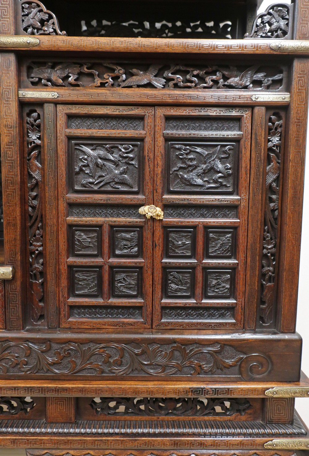 A dark carved hardwood Japanese Meiji period shodana cabinet featuring asymmetrical shelves, relief-carved panel doors, metal mounts, and a carved lower base. View XIII