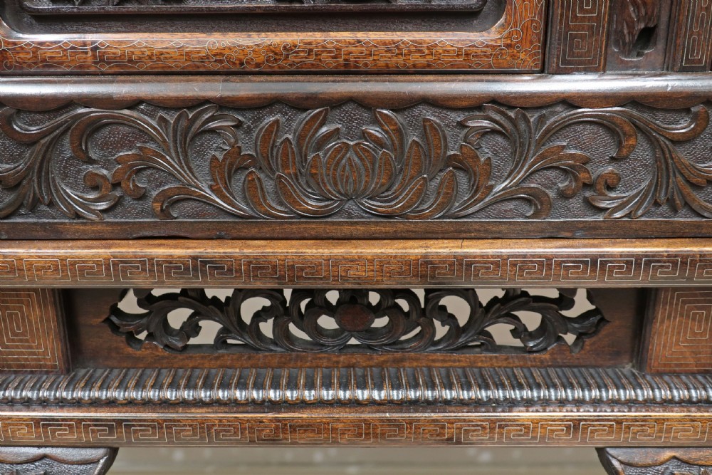 A dark carved hardwood Japanese Meiji period shodana cabinet featuring asymmetrical shelves, relief-carved panel doors, metal mounts, and a carved lower base. View XVI