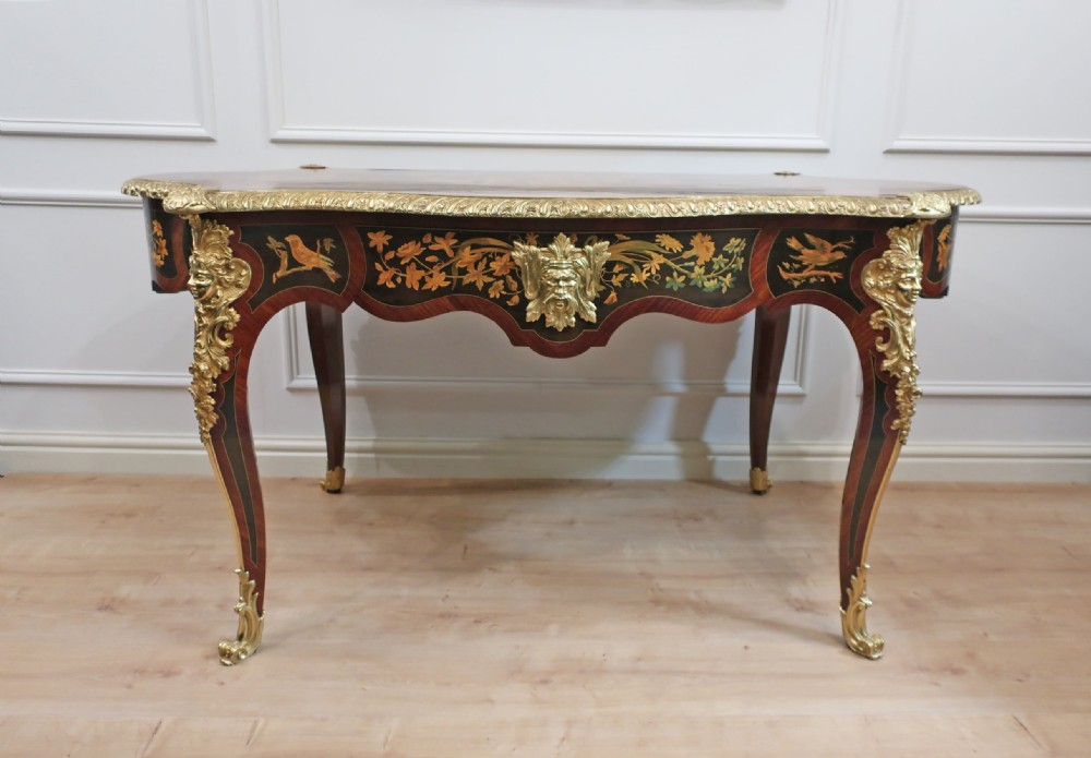 A French Louis XV style writing table featuring a serpentine top with floral marquetry inlay, cabriole legs, and gilt-bronze mounts. View XVII
