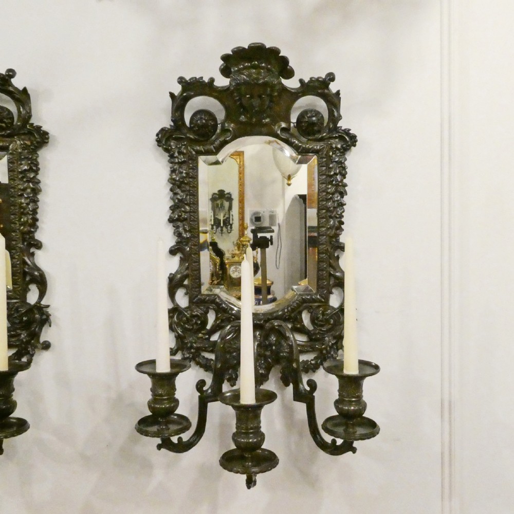 A pair of dark patinated bronze wall girandoles with ornate foliate frames surrounding central mirrored plates and three candle branches each. View III