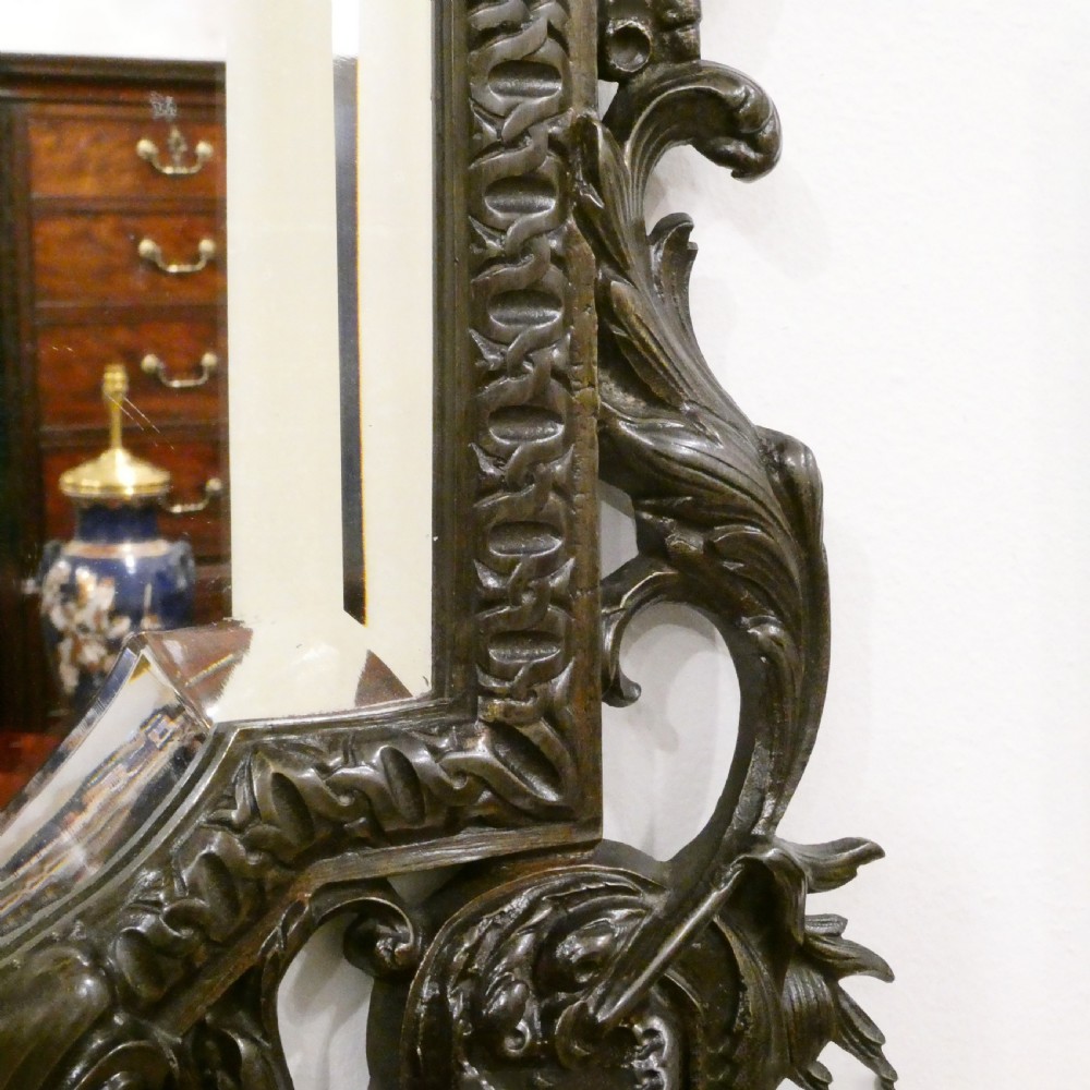 A pair of dark patinated bronze wall girandoles with ornate foliate frames surrounding central mirrored plates and three candle branches each. View IX