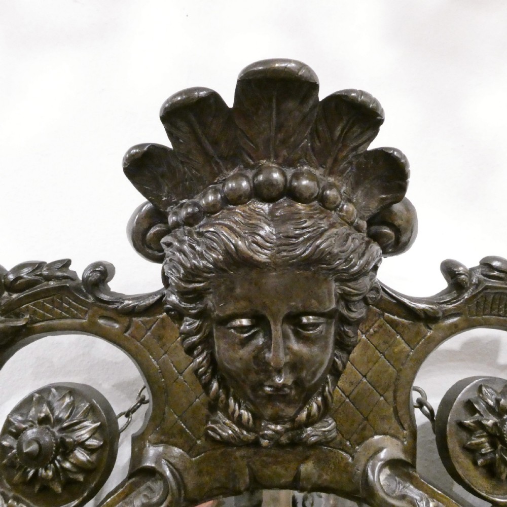 A pair of dark patinated bronze wall girandoles with ornate foliate frames surrounding central mirrored plates and three candle branches each. View XII