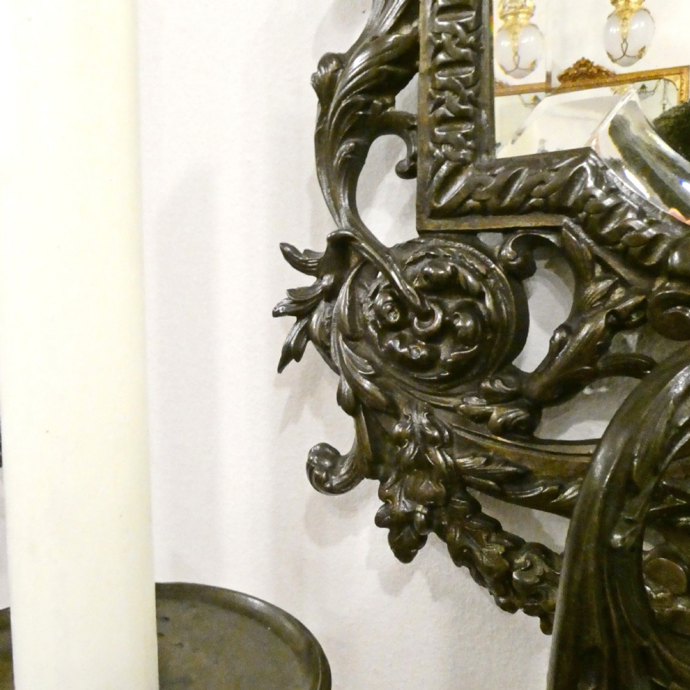 A pair of dark patinated bronze wall girandoles with ornate foliate frames surrounding central mirrored plates and three candle branches each. View XIV