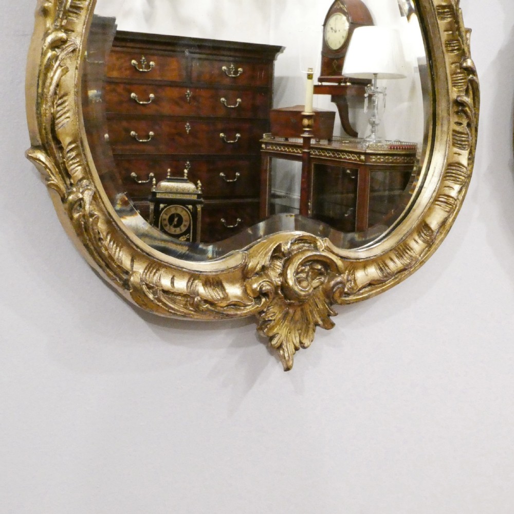 A pair of ornate French Rococo style wall mirrors featuring carved giltwood frames with scrollwork crests and lattice detailing. View IV