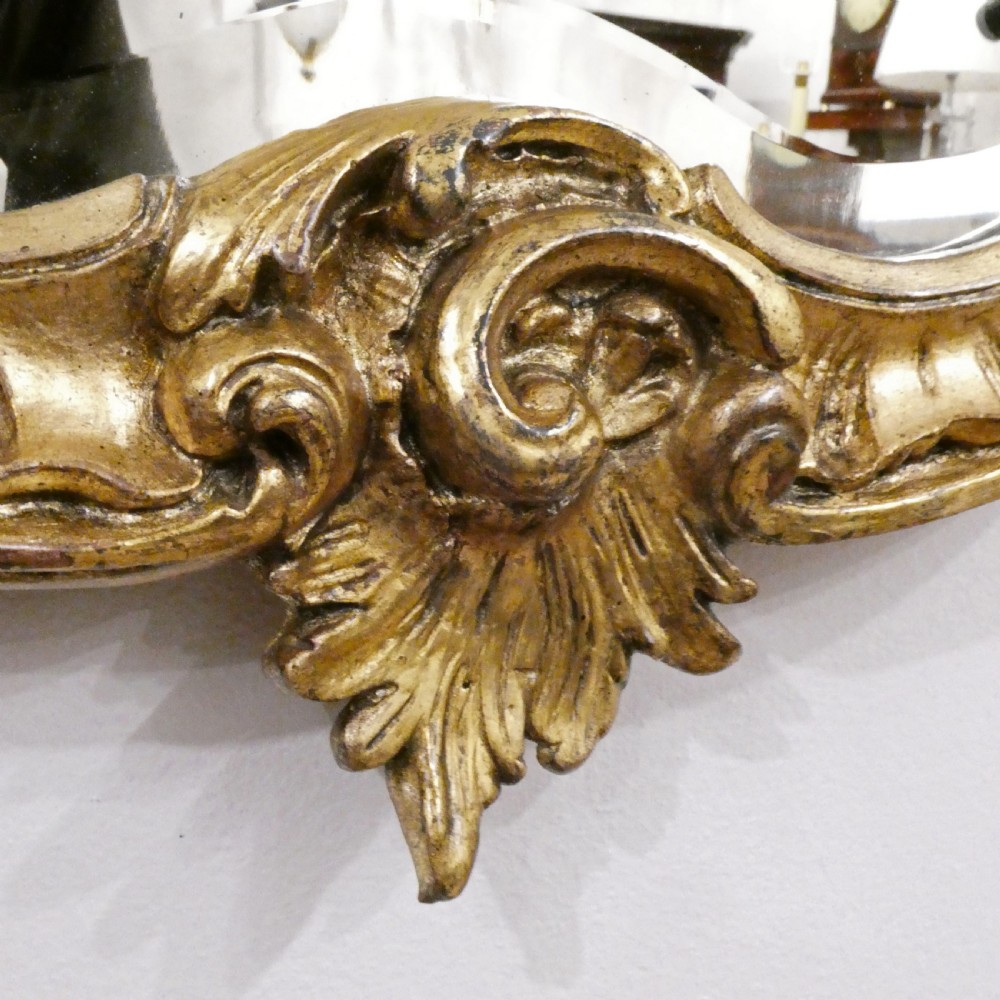 A pair of ornate French Rococo style wall mirrors featuring carved giltwood frames with scrollwork crests and lattice detailing. View V