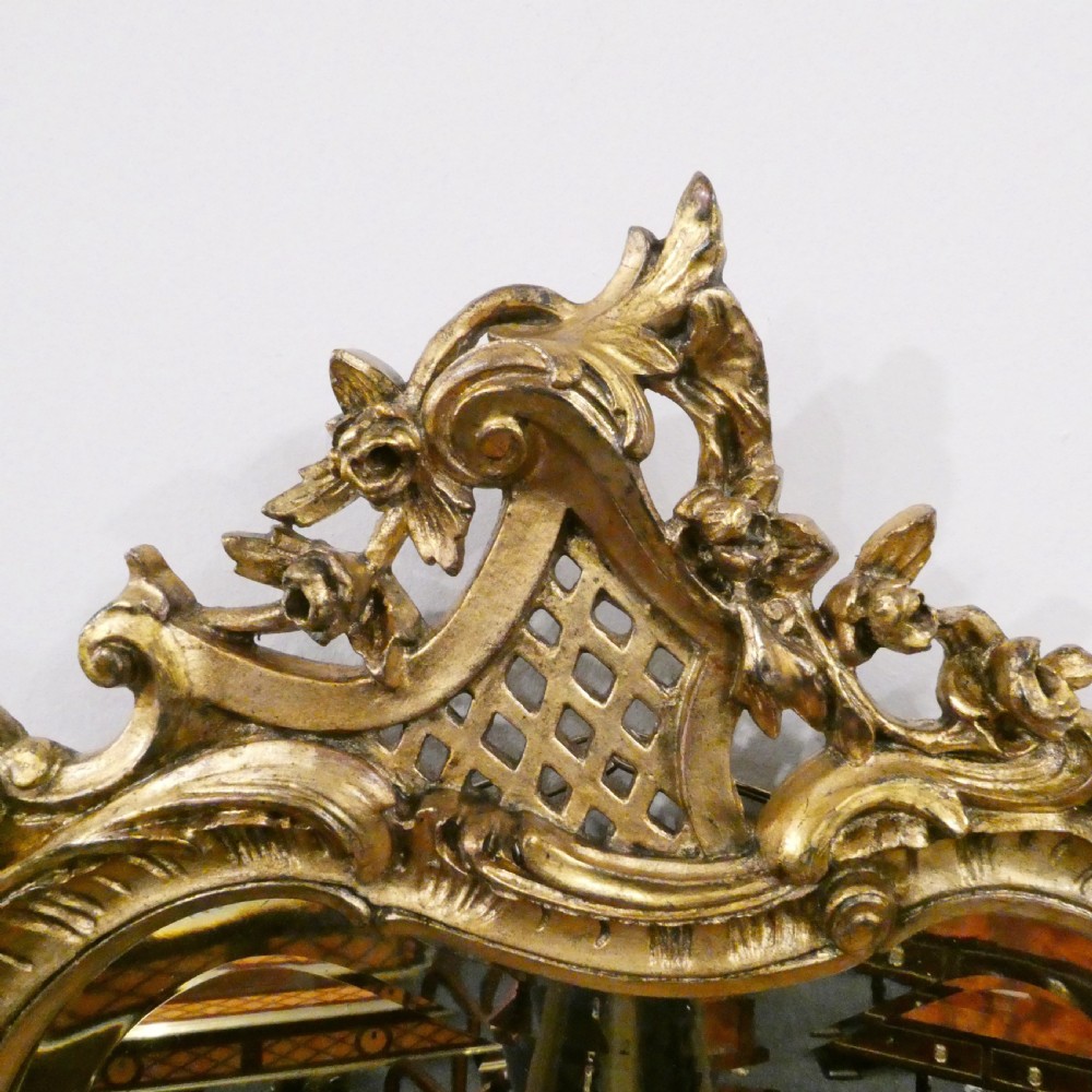A pair of ornate French Rococo style wall mirrors featuring carved giltwood frames with scrollwork crests and lattice detailing. View VIII