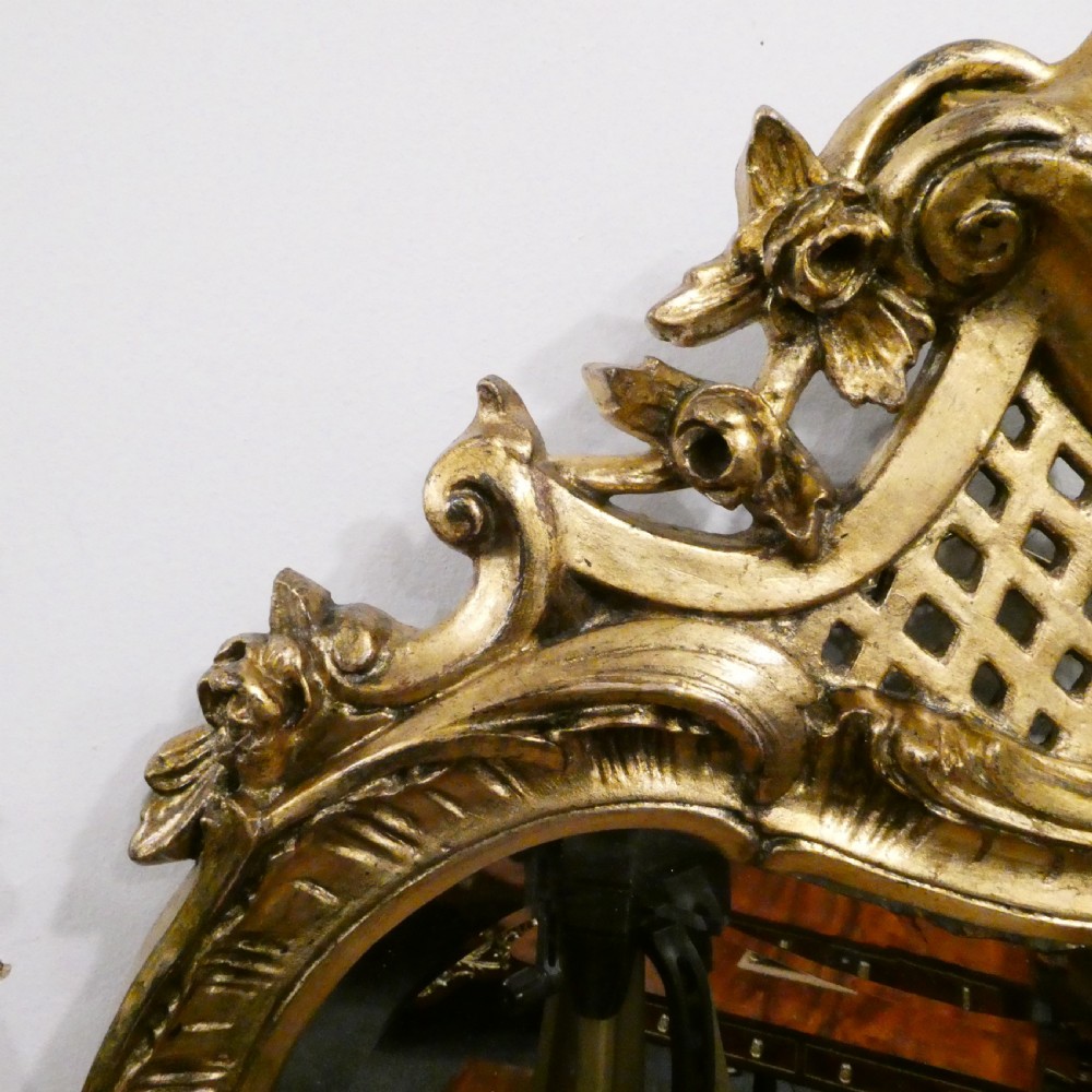 A pair of ornate French Rococo style wall mirrors featuring carved giltwood frames with scrollwork crests and lattice detailing. View IX