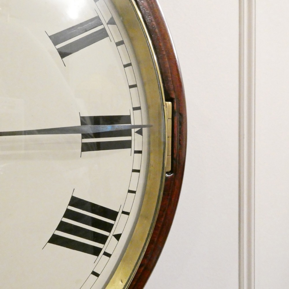 A circular Georgian wall clock featuring a mahogany surround, brass bezel, white dial with Roman numerals, and signature reading James Murray London. View V