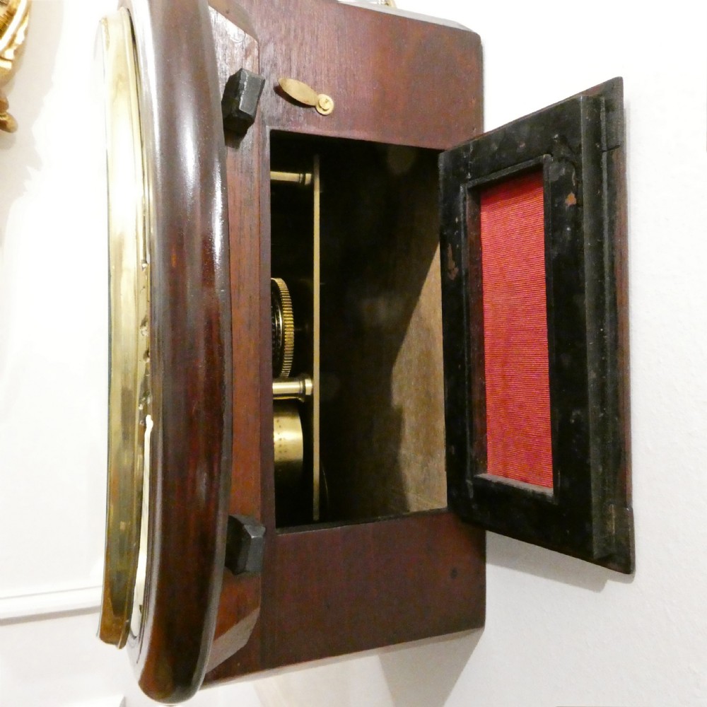 A circular Georgian wall clock featuring a mahogany surround, brass bezel, white dial with Roman numerals, and signature reading James Murray London. View VI