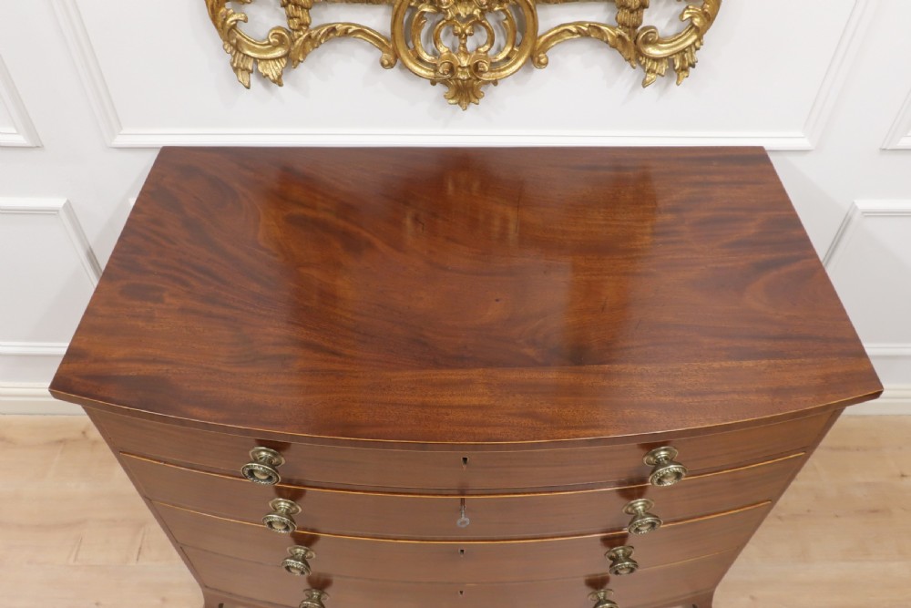 A Georgian mahogany bow-fronted chest of drawers featuring four graduated drawers with circular brass ring handles and splayed bracket feet. View VI