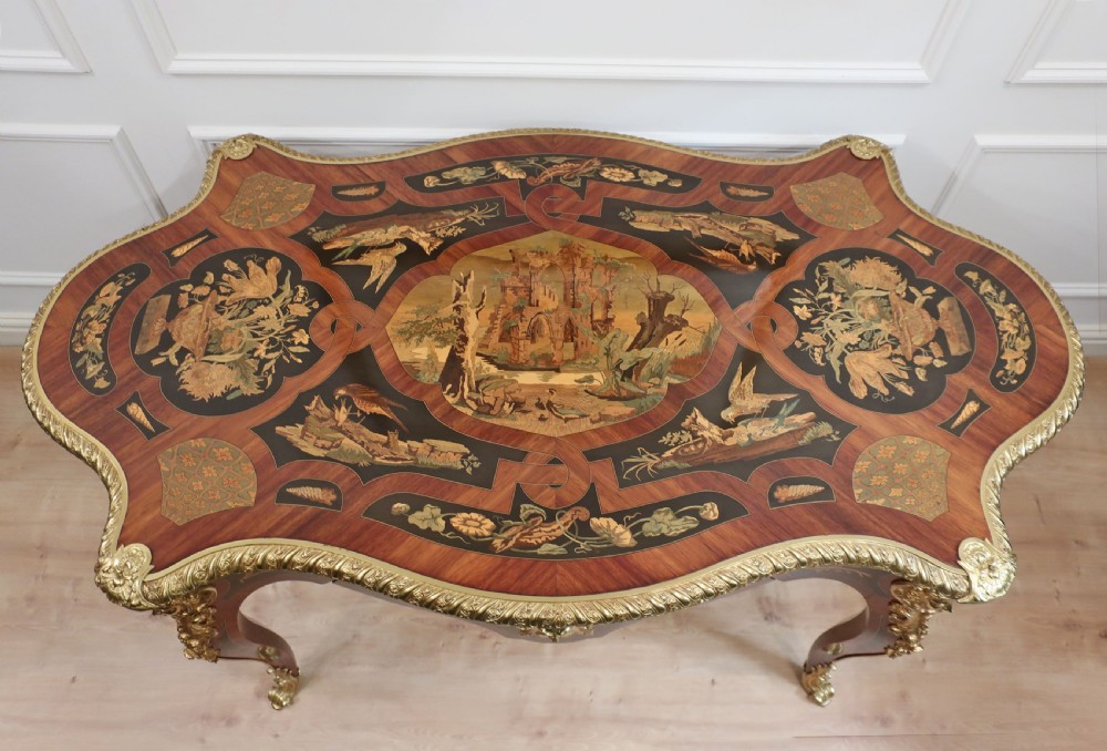 A French Louis XV style bureau plat writing table decorated with intricate floral marquetry inlay, sweeping cabriole legs, and ornate gilt-bronze mounts. View II