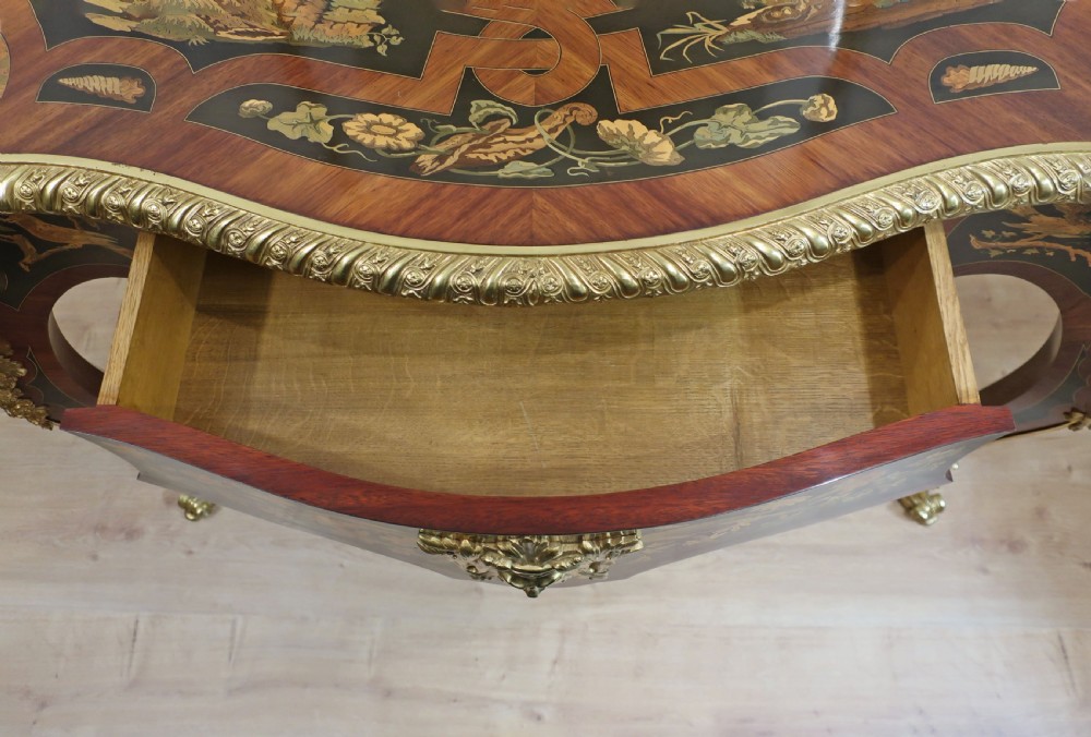 A French Louis XV style bureau plat writing table decorated with intricate floral marquetry inlay, sweeping cabriole legs, and ornate gilt-bronze mounts. View XIII