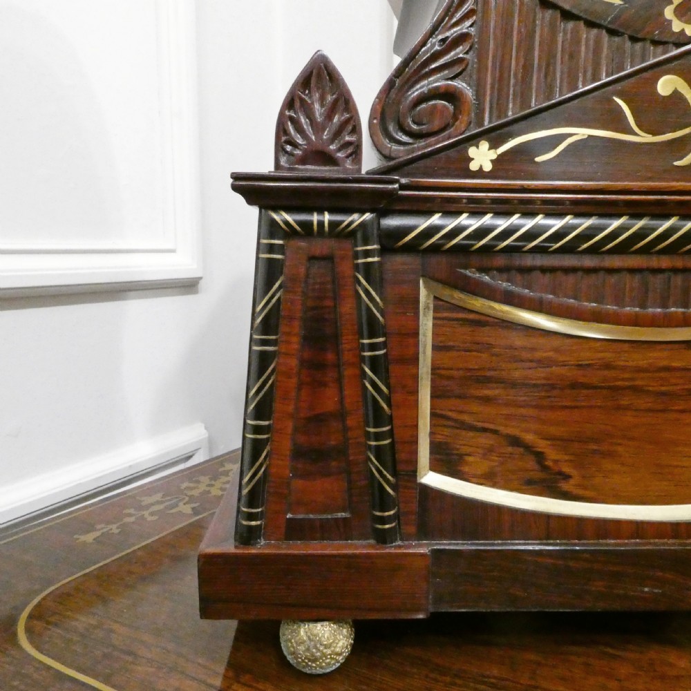 A Georgian rosewood bracket clock featuring intricate brass inlay, a brass pineapple finial, a white circular dial with Roman numerals, and brass ball feet. View IV