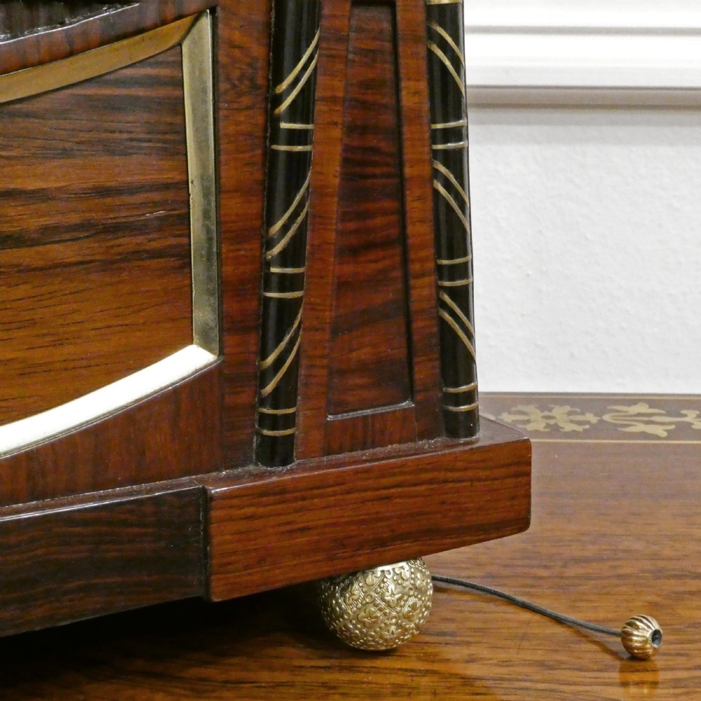 A Georgian rosewood bracket clock featuring intricate brass inlay, a brass pineapple finial, a white circular dial with Roman numerals, and brass ball feet. View V