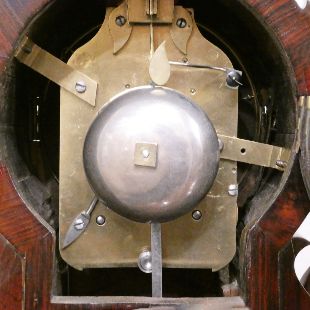 A Georgian rosewood bracket clock featuring intricate brass inlay, a brass pineapple finial, a white circular dial with Roman numerals, and brass ball feet. View XII