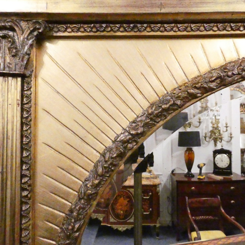 A rectangular giltwood overmantel wall mirror featuring a classical relief frieze above a central circular mirror plate flanked by two rectangular mirrored sections. View IV