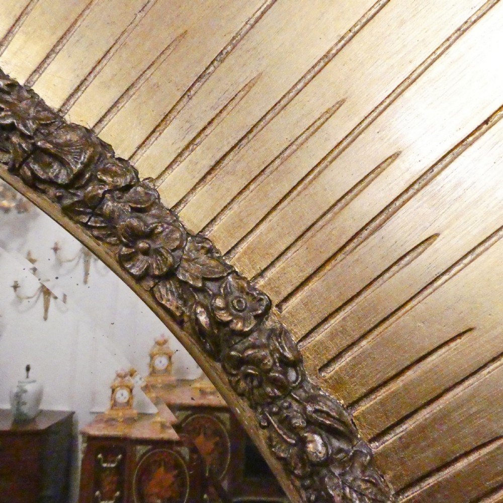 A rectangular giltwood overmantel wall mirror featuring a classical relief frieze above a central circular mirror plate flanked by two rectangular mirrored sections. View V