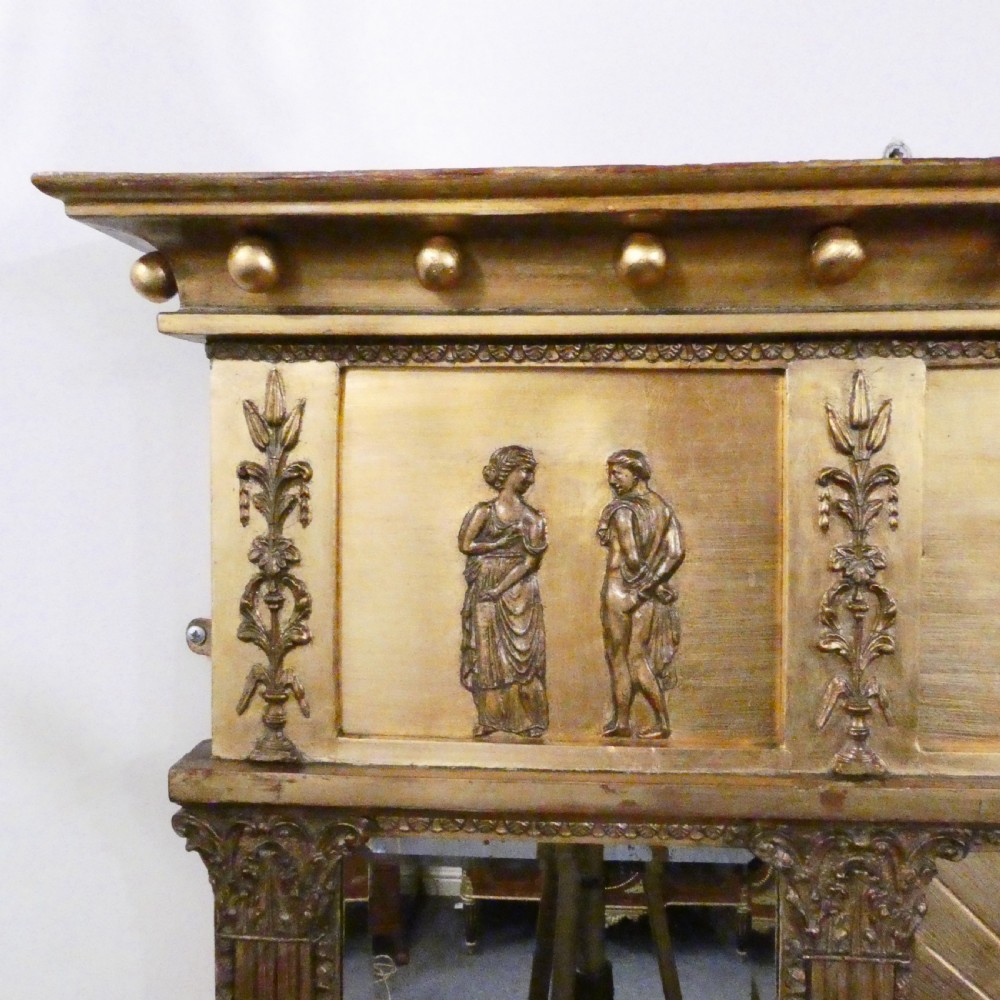 A rectangular giltwood overmantel wall mirror featuring a classical relief frieze above a central circular mirror plate flanked by two rectangular mirrored sections. View IX