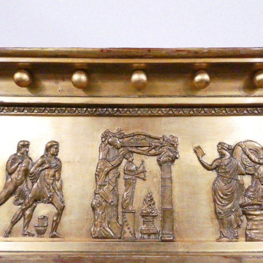 A rectangular giltwood overmantel wall mirror featuring a classical relief frieze above a central circular mirror plate flanked by two rectangular mirrored sections. View XIII