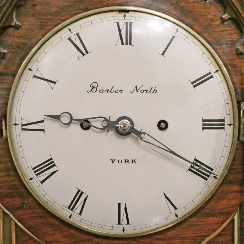 A dark rosewood William IV bracket clock featuring a gothic arch top, brass finials, brass feet, and a white dial signed Barber and North of York. View III