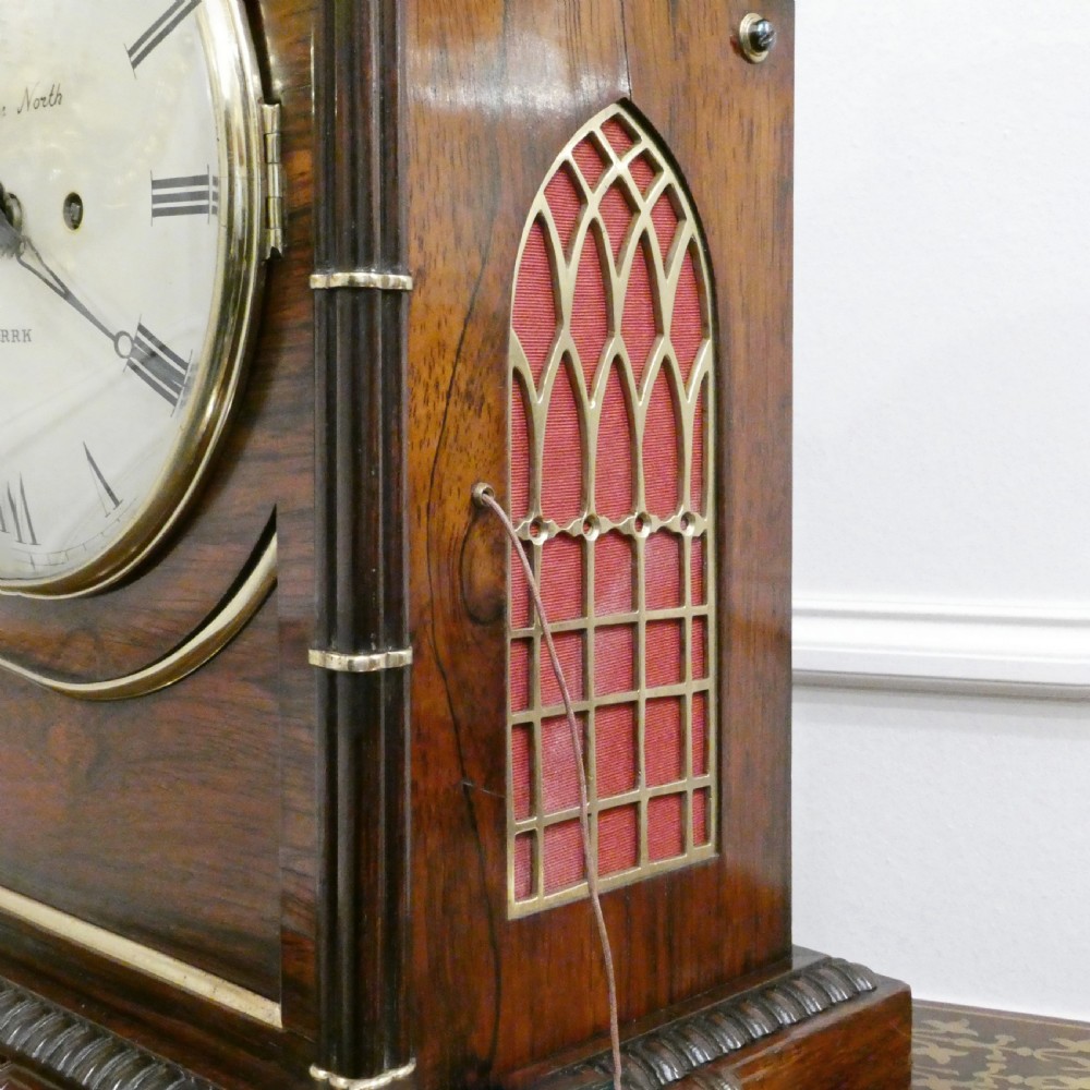 A dark rosewood William IV bracket clock featuring a gothic arch top, brass finials, brass feet, and a white dial signed Barber and North of York. View XI