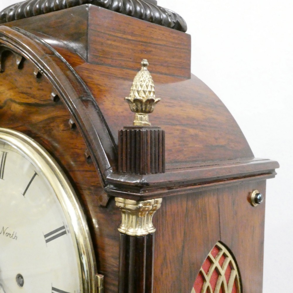 A dark rosewood William IV bracket clock featuring a gothic arch top, brass finials, brass feet, and a white dial signed Barber and North of York. View XII