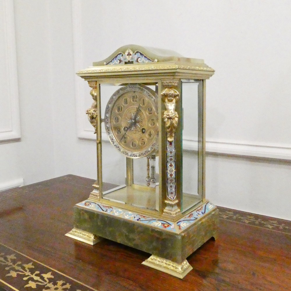 A late nineteenth-century French four-glass mantel clock featuring a green onyx base and top, champleve enamel borders, and a visible mercury pendulum. View II