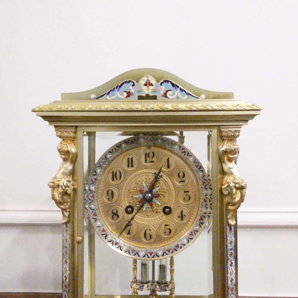 A late nineteenth-century French four-glass mantel clock featuring a green onyx base and top, champleve enamel borders, and a visible mercury pendulum. View V