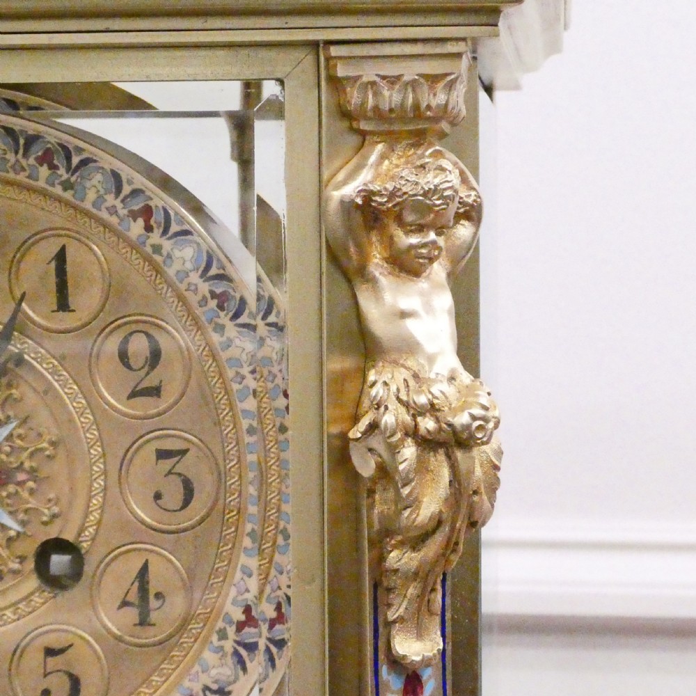 A late nineteenth-century French four-glass mantel clock featuring a green onyx base and top, champleve enamel borders, and a visible mercury pendulum. View VI