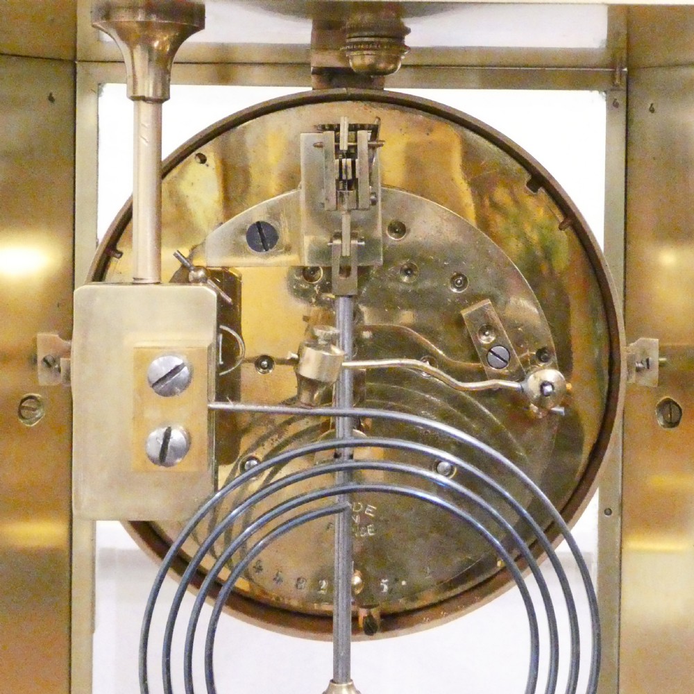 A late nineteenth-century French four-glass mantel clock featuring a green onyx base and top, champleve enamel borders, and a visible mercury pendulum. View XVI