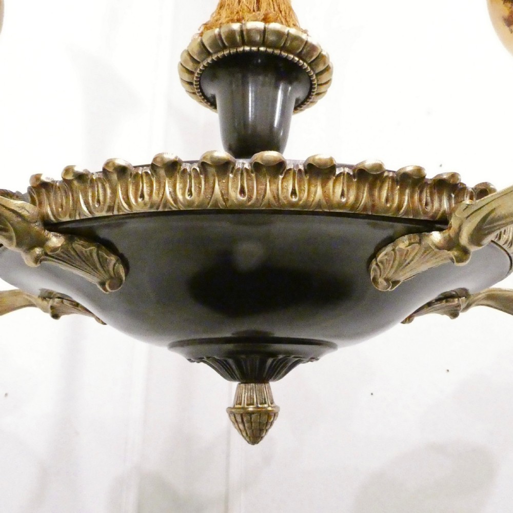 An Art Deco bronze chandelier featuring carved alabaster shade cups suspended from a corded stem with decorative tassel detail. View VI