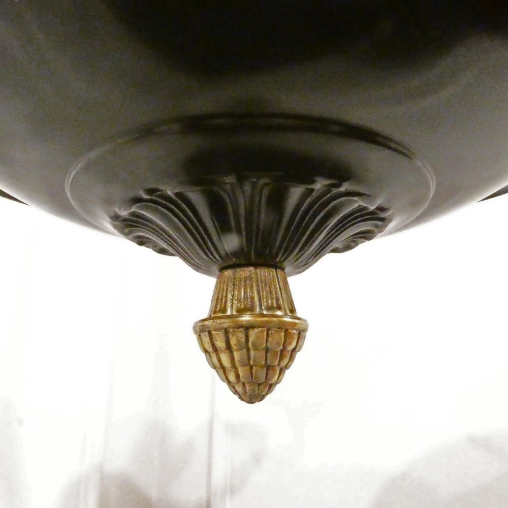 An Art Deco bronze chandelier featuring carved alabaster shade cups suspended from a corded stem with decorative tassel detail. View X