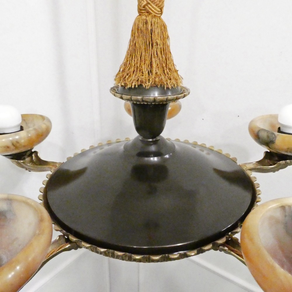 An Art Deco bronze chandelier featuring carved alabaster shade cups suspended from a corded stem with decorative tassel detail. View XII